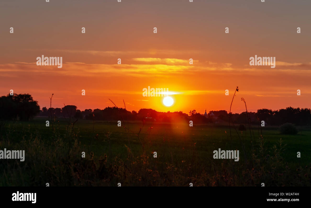 Sky con un sole al tramonto in estate calda serata brillante tramonto sul cielo blu Foto Stock