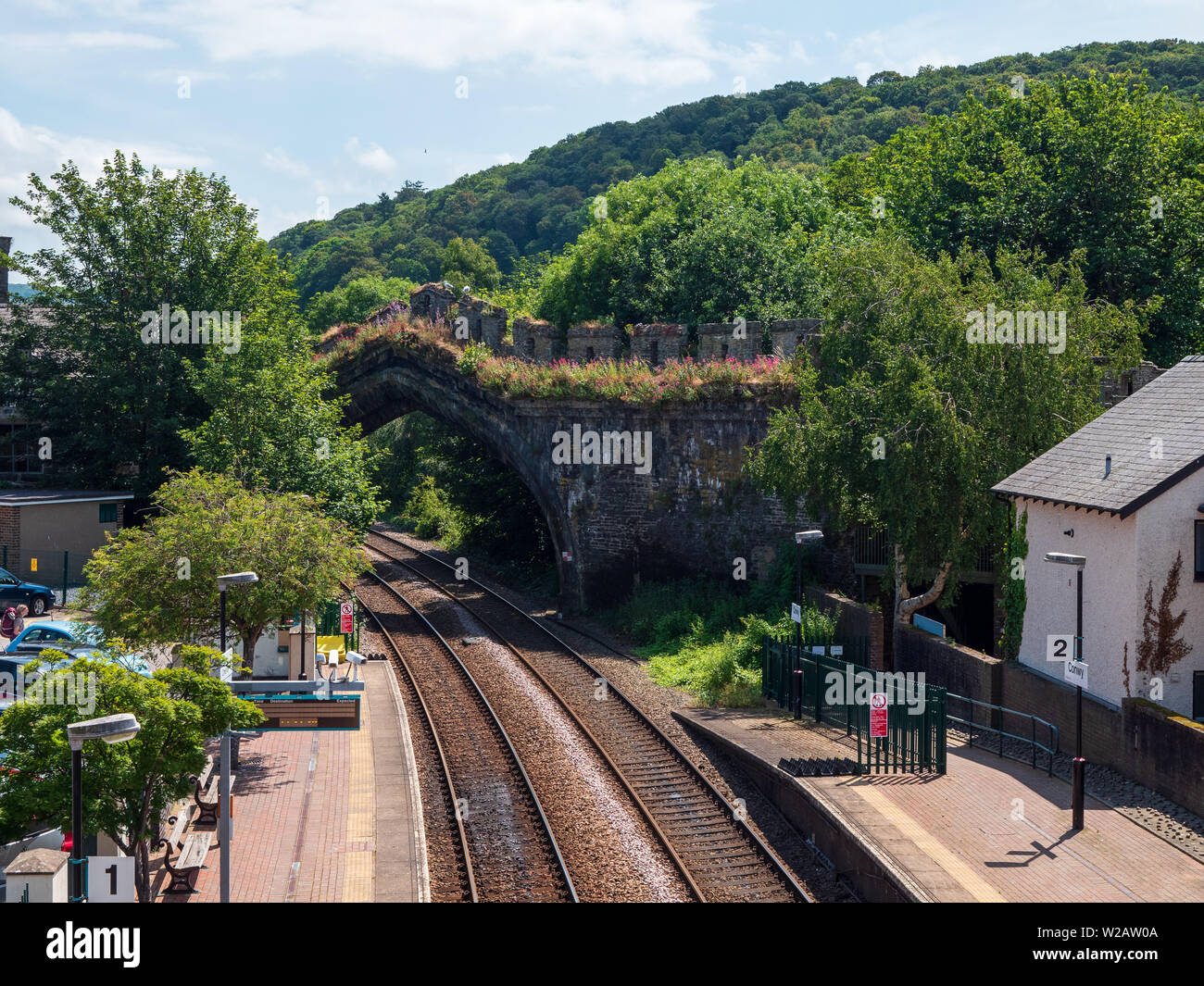 Conwy, Wales, Regno Unito - La linea ferroviaria a Conwy passa sotto un arco per ottenere attraverso le località di mura medievali. Foto Stock