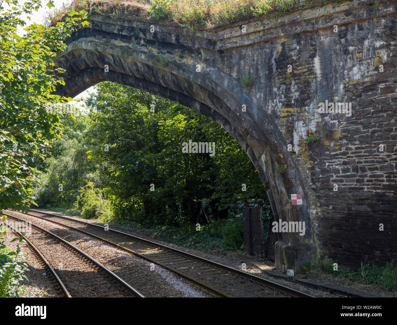 Conwy, Wales, Regno Unito - La linea ferroviaria a Conwy passa sotto un arco per ottenere attraverso le località di mura medievali. Foto Stock