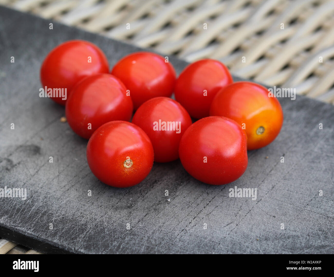 Close up rosso fresco di pomodoro ciliegino nero sul bordo di taglio sullo sfondo Foto Stock