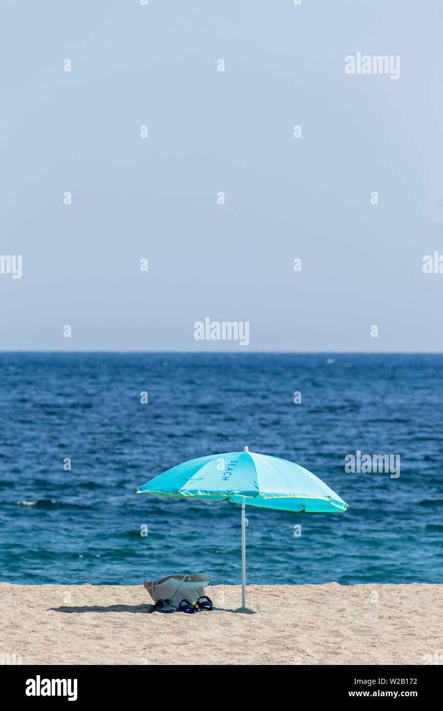 Blue ombrellone sulla spiaggia con borsa da spiaggia e della zona bikini Foto Stock