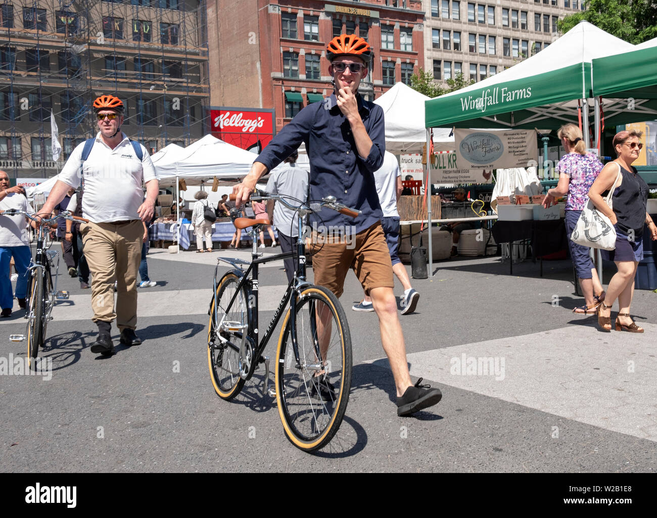 Due uomini possibilmente correlati, a piedi le loro biciclette identici attraverso la Piazza Unione Mercato verde a Manhattan, New York City Foto Stock