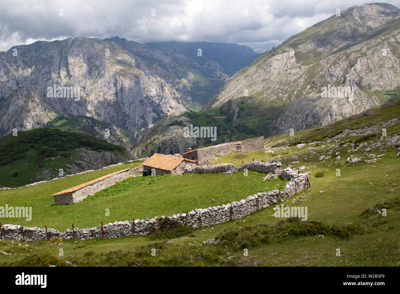 Edifici agricoli alpini e mura in pietra a secco sopra il villaggio di Bejes, Parco Nazionale Picos de Europa, Spagna Foto Stock