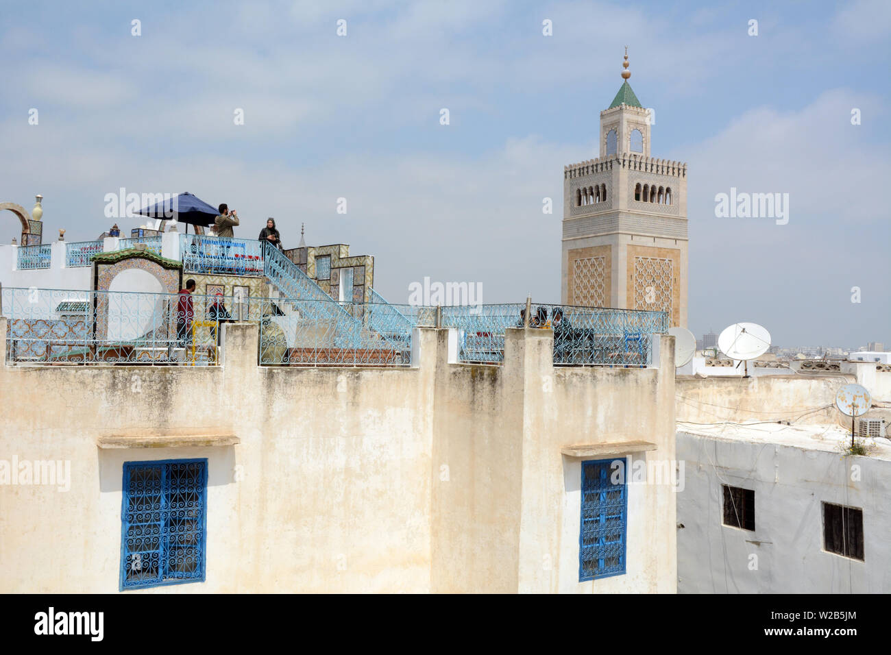 Tunisini prendendo in una vista sui tetti di Tunisi città vecchia medina e si affaccia la moschea Zeitoun, visto da un cafe' all'aperto, Tunisia. Foto Stock