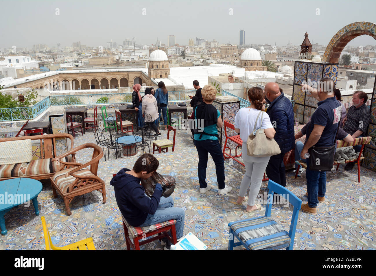 Tunisini prendendo in una vista sui tetti di Tunisi città vecchia medina e si affaccia la moschea Zeitoun, visto da un cafe' all'aperto, Tunisia. Foto Stock