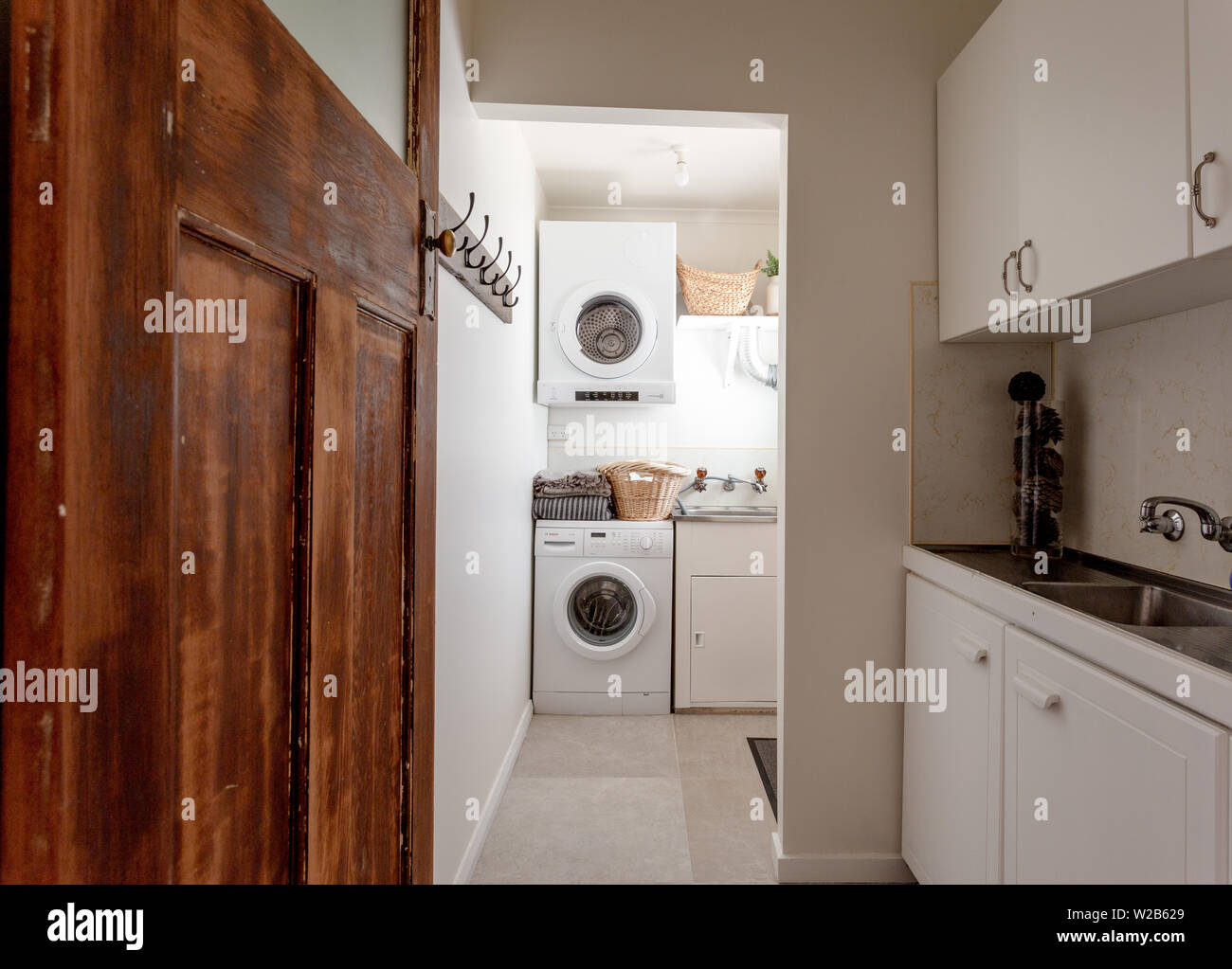 White servizio lavanderia / ripostiglio con paese porta e lavatrice e asciugatrice Foto Stock