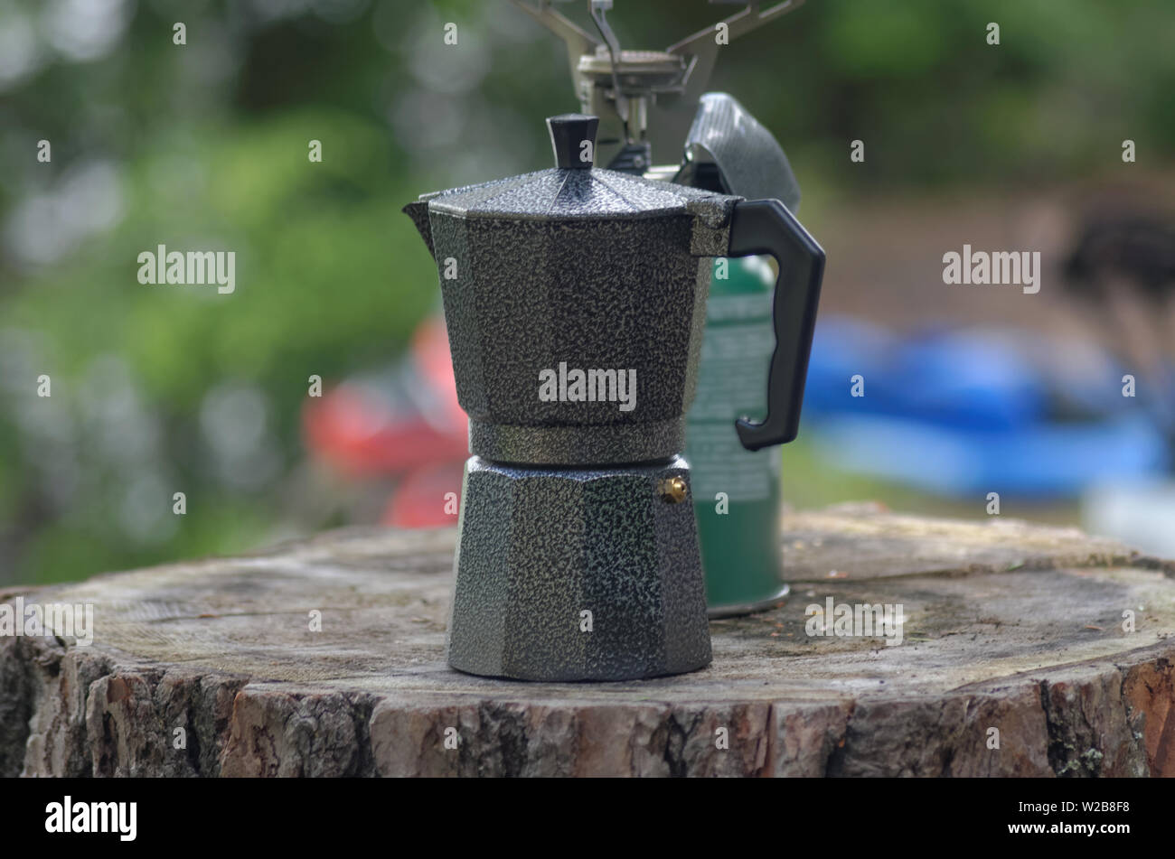 Un caffè espresso di pentola e singolo bruciatore camp stufa su un log Foto Stock