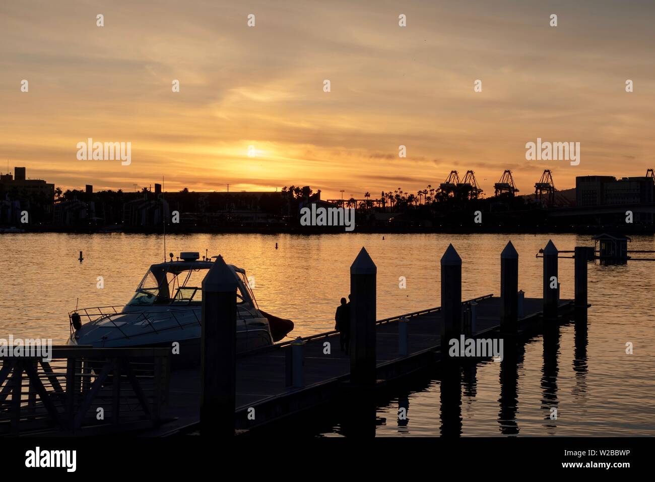 Imbarcazione attraccata ad una banchina con il Porto di Los Angeles in background durante il tramonto Foto Stock
