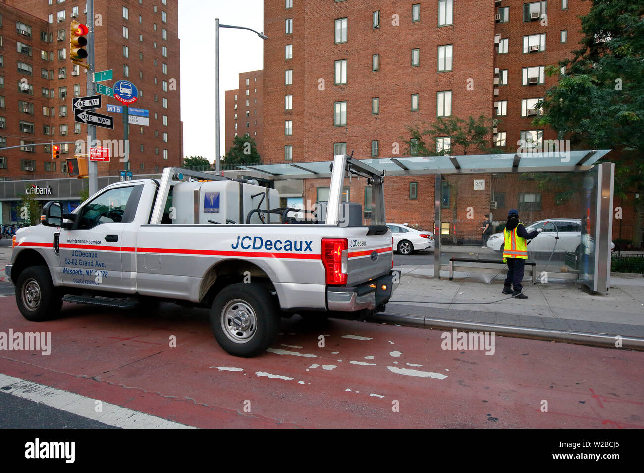 Un lavoratore di JCDecaux pulizia di una fermata bus shelter in New York City Foto Stock