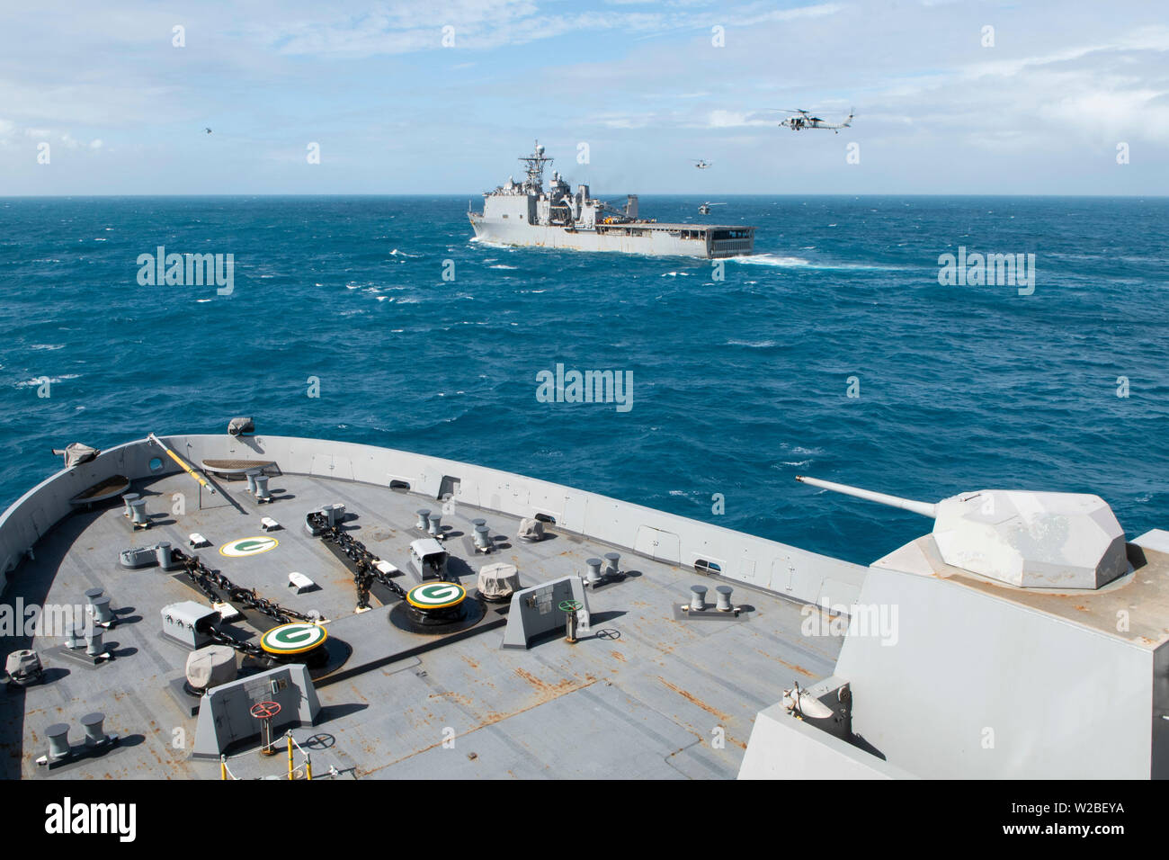 190707-N-DX072-1120 CORAL SEA (Luglio 7, 2019) UH-1Y Huey elicotteri, assegnato al trentunesimo Marine Expeditionary Unit (MEU)'Dragons' del mezzo marino Tiltrotor Squadron (VMM) 265 (rinforzato), e MH-60S Sea Hawk elicotteri, assegnato al "Isola Cavalieri" di elicottero di mare squadrone di combattimento (HSC) 25, passare il puntatore del mouse vicino al dock di anfibio sbarco nave USS Ashland (LSD 48) durante una visita, scheda, ricerca e sequestro (VBSS) Praticare con il trasporto anfibio dock nave USS Green Bay (LPD 20). Green Bay e Ashland, parte della Vespa Anfibia Gruppo pronto, con avviato 31 MEU, sono operanti nell'indo-P Foto Stock