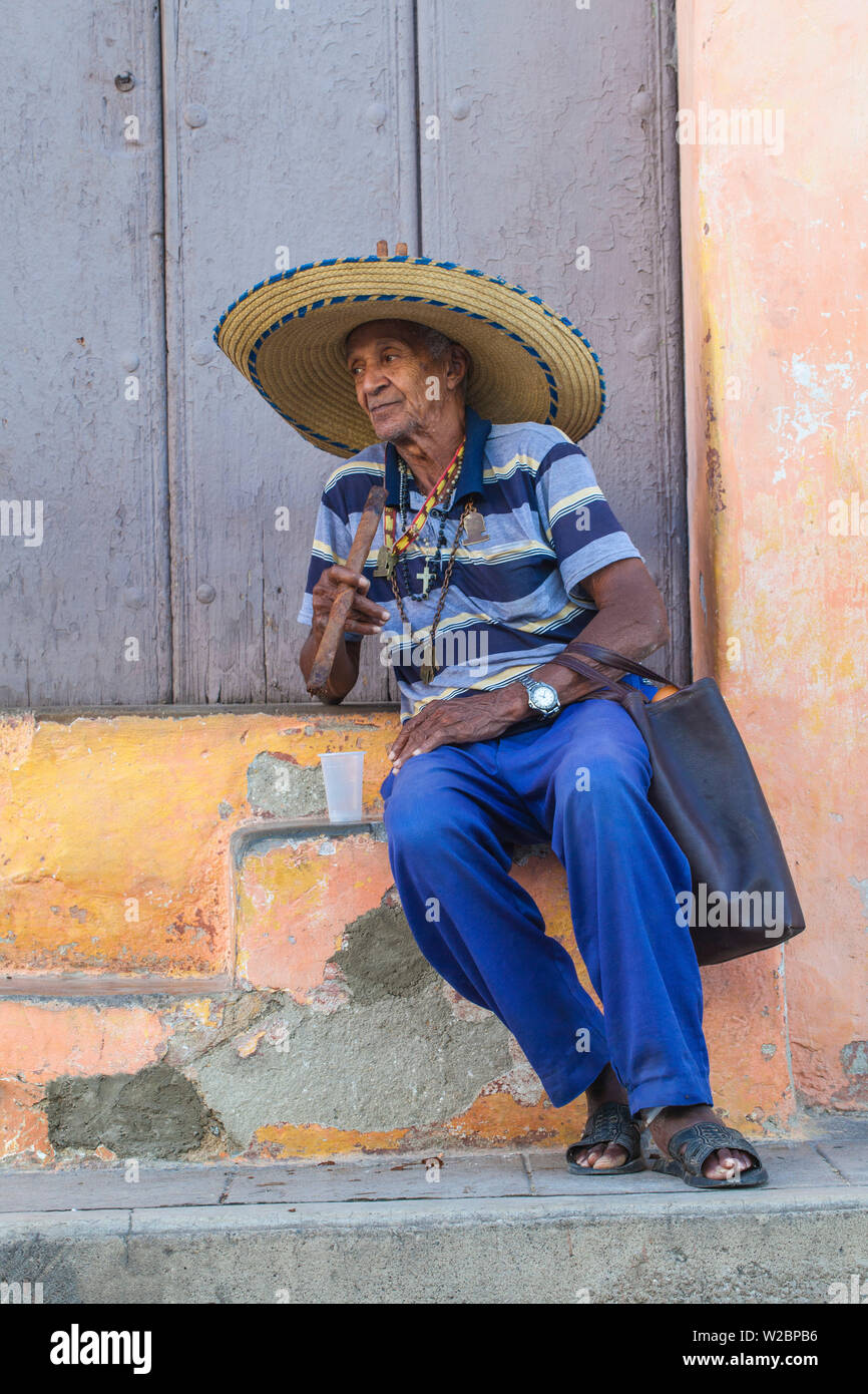 Cuba, Camaguey, provincia di Camaguey, Plaza San Juan de Dios, Ederly uomo seduto sui gradini di fumare sigari cubani Foto Stock