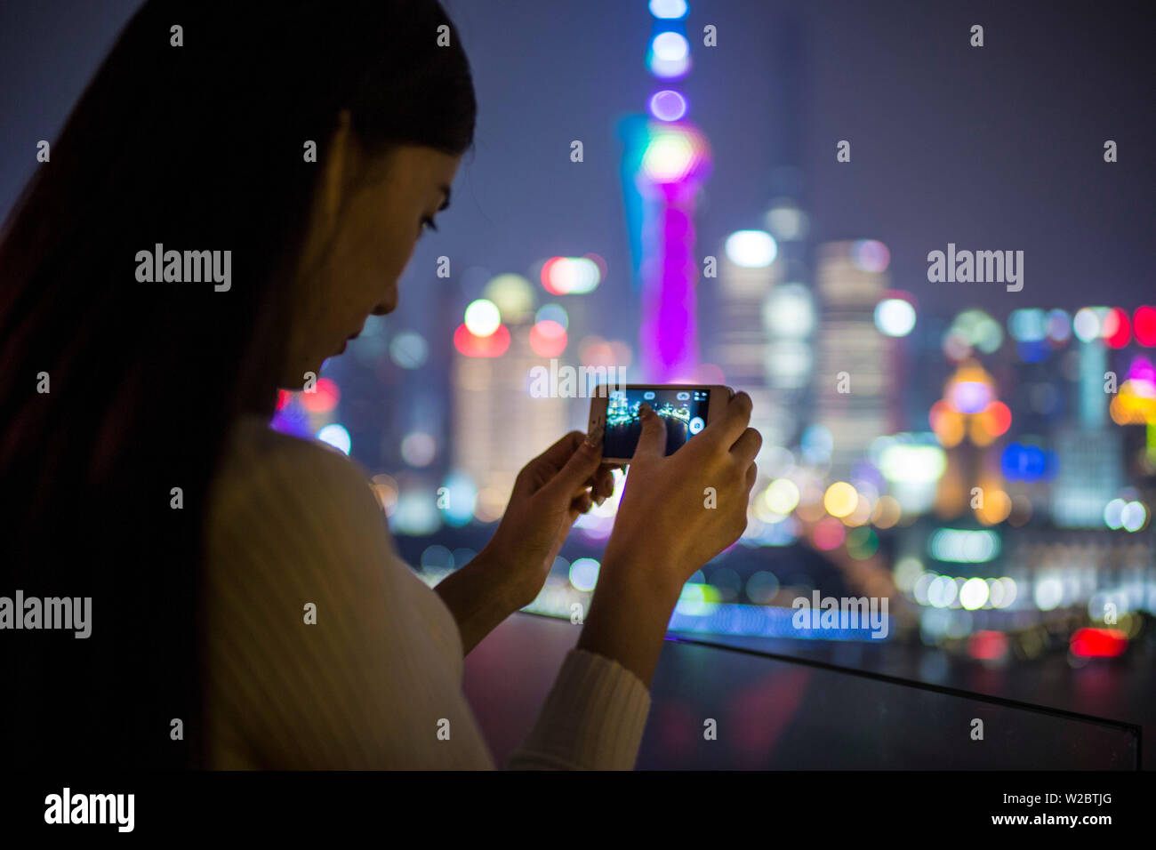 Donna di scattare le foto con lo smartphone infornt della skyline di Pudong, Shanghai, Cina (MR) Foto Stock