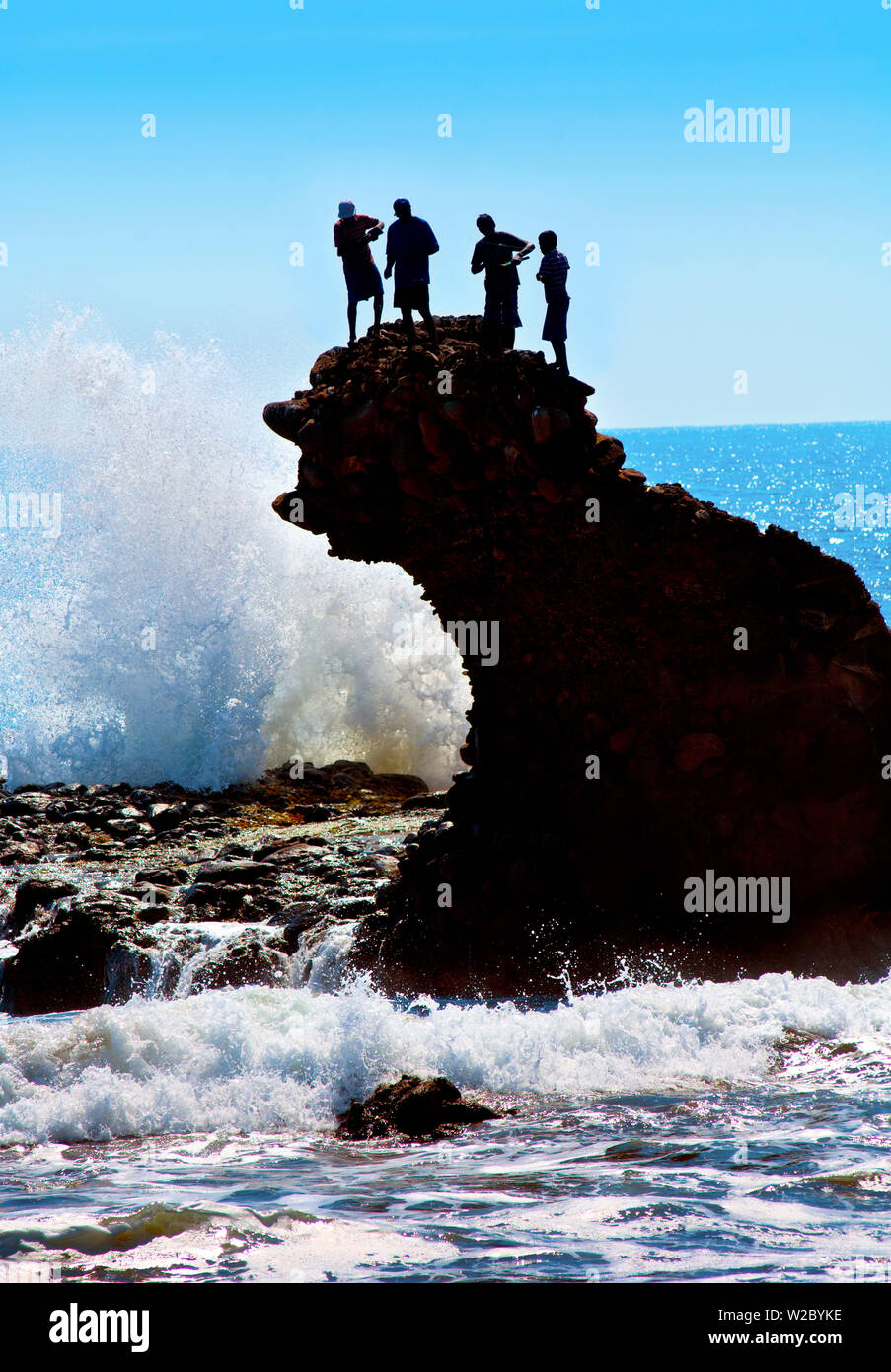 Playa El Tunco, El Salvador, Pacific Ocean Beach, popolare tra i surfisti, grandi onde, chiamato dopo la formazione di roccia, bambini locali la pesca dalla parte superiore della formazione di roccia Foto Stock