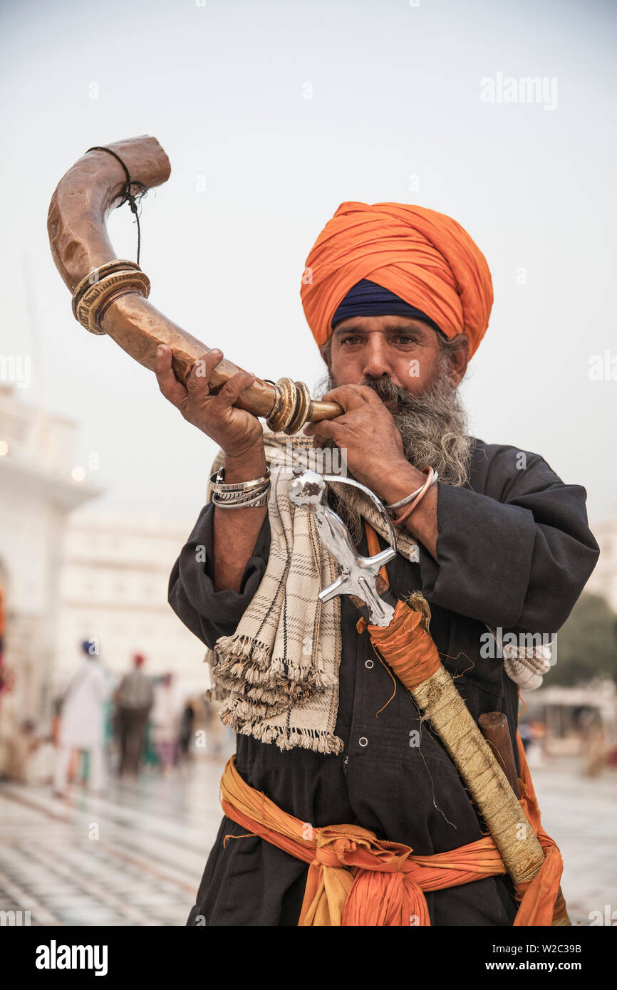 India Punjab, Amritsar e pellegrino soffia lo strumento musicale all'Harmandir Sahib, noto come il Tempio d'Oro Foto Stock