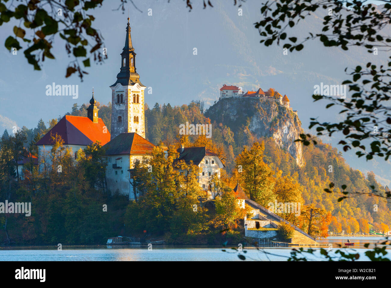 Isola di Bled (Blejski Otok) con la Chiesa dell'Assunzione (Cerkev Marijinega vnebovzetja) & Castello di Bled illuminata di Sunrise, lago di Bled Bled, Alta Carniola, sulle Alpi Giulie, Slovenia Foto Stock