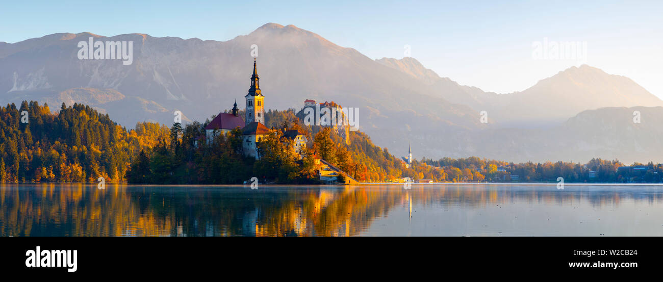 Isola di Bled (Blejski Otok) con la Chiesa dell'Assunzione (Cerkev Marijinega vnebovzetja) & Castello di Bled illuminata di Sunrise, lago di Bled Bled, Alta Carniola, sulle Alpi Giulie, Slovenia Foto Stock