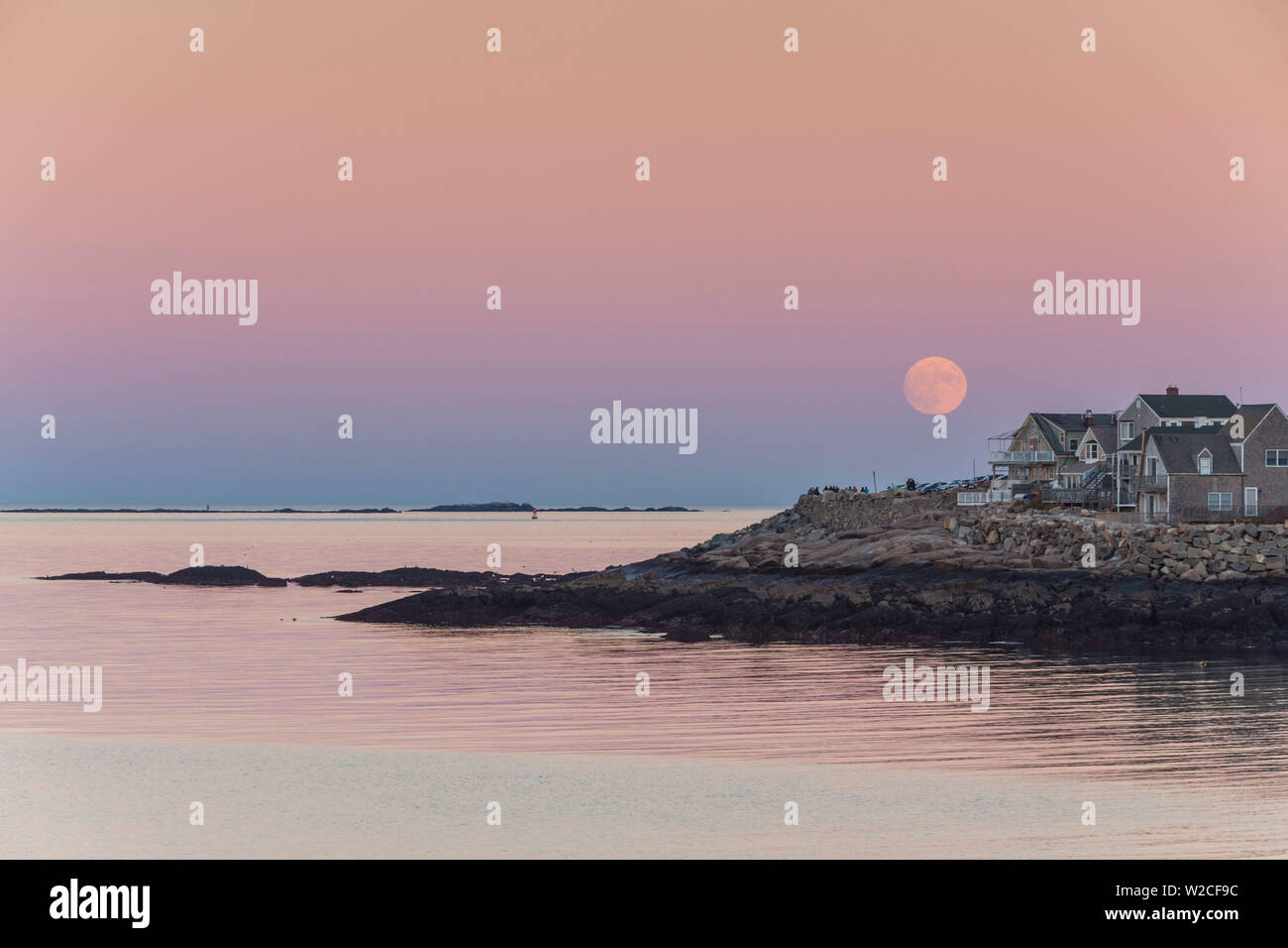 Stati Uniti d'America, Massachusetts, Cape Ann, Rockport, sorgere della luna su edifici sul collo Bearskin, crepuscolo Foto Stock
