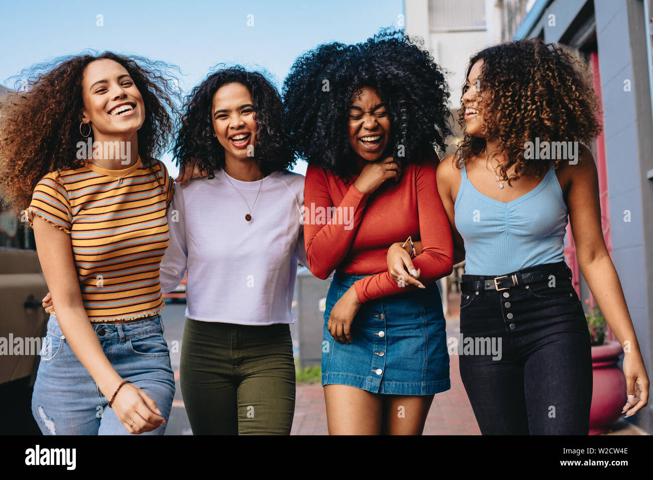 Multirazziale gruppo di amici a piedi giù per la strada della citta'. Quattro giovani donne passeggiate all'aperto sulla strada avendo divertimento. Foto Stock