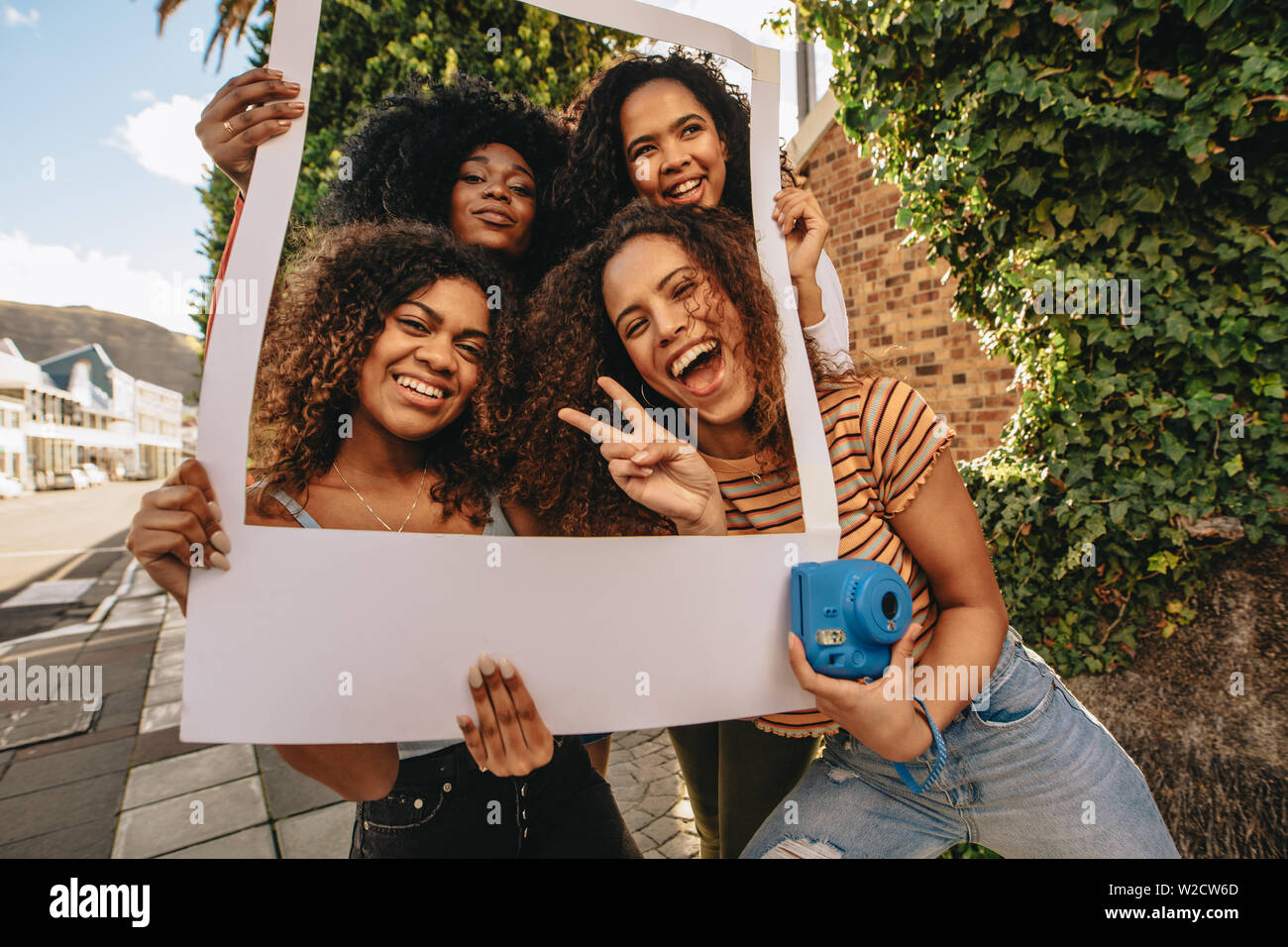 Emozionato amici di sesso femminile in posa con vuoto photo frame. Ragazze sorridenti con vuoto cornice immagine all'aperto nella città. Foto Stock