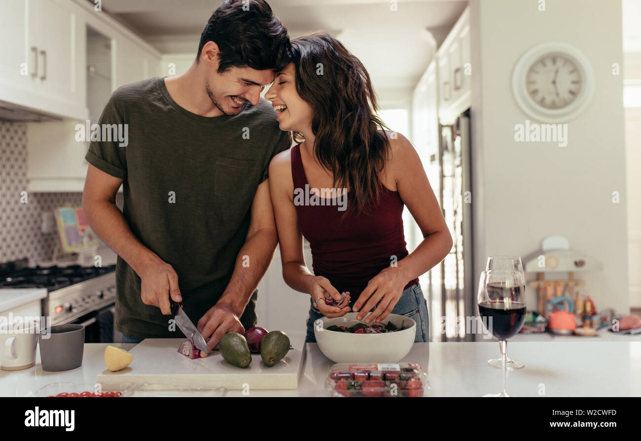 Amorevole coppia giovane tagliare le verdure insieme al banco di cucina. Giovane uomo e donna innamorata di cottura degli alimenti insieme a casa. Foto Stock