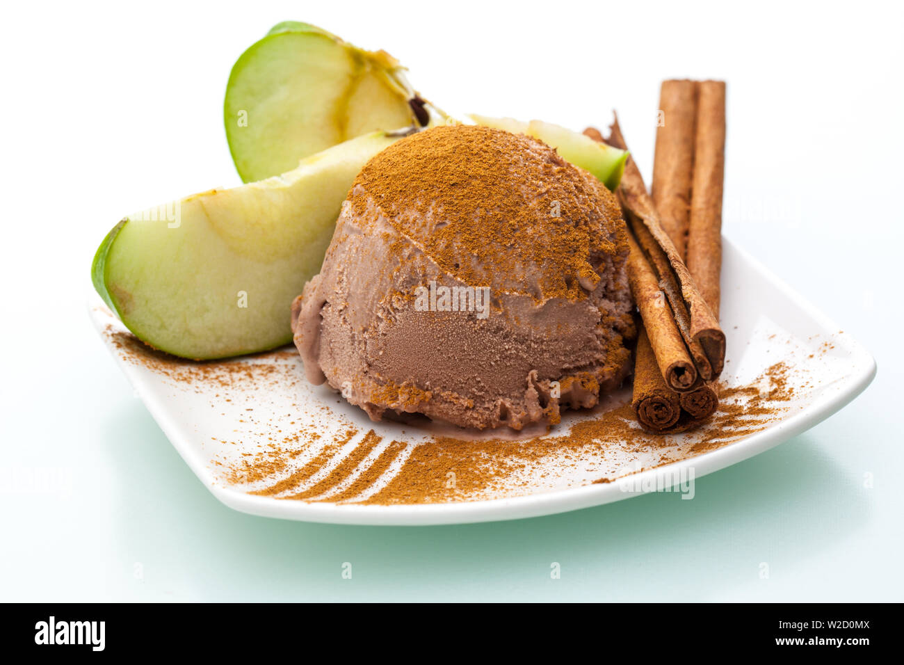 Gelato gelato: un unico convogliatore di apple gelato alla cannella con fette di mela e un bastoncino di cannella su una piastra su sfondo bianco Foto Stock
