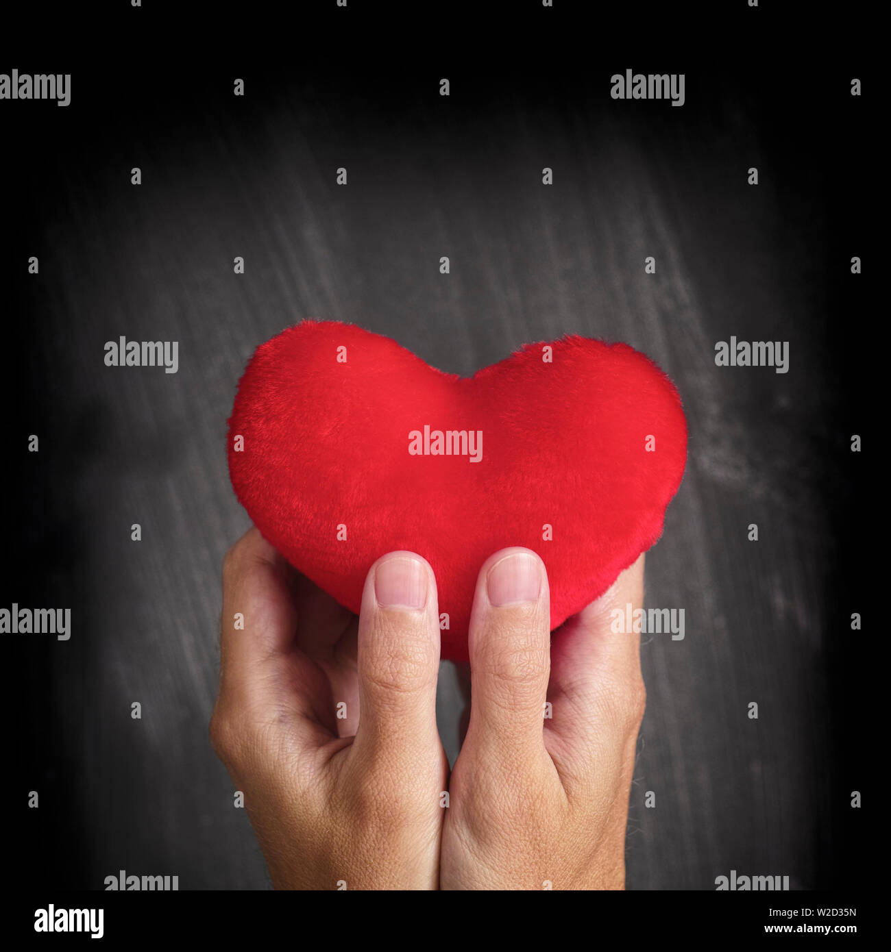 Uomo con cuore rosso nelle sue mani. Square crop. Foto Stock
