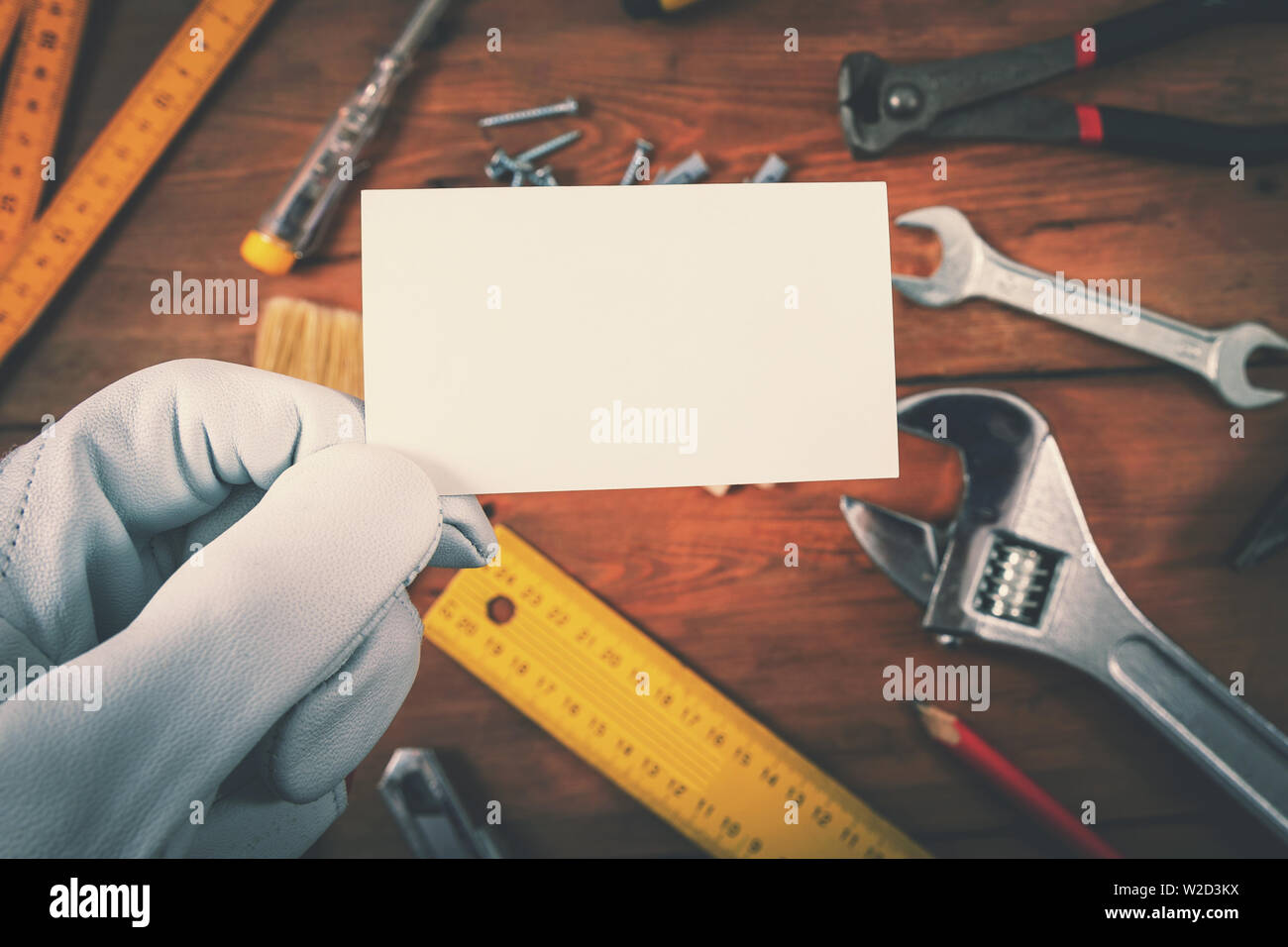 Costruzione casa e servizi di riparazione - lavoratore azienda blank business card su strumenti di lavoro su sfondo di legno Foto Stock