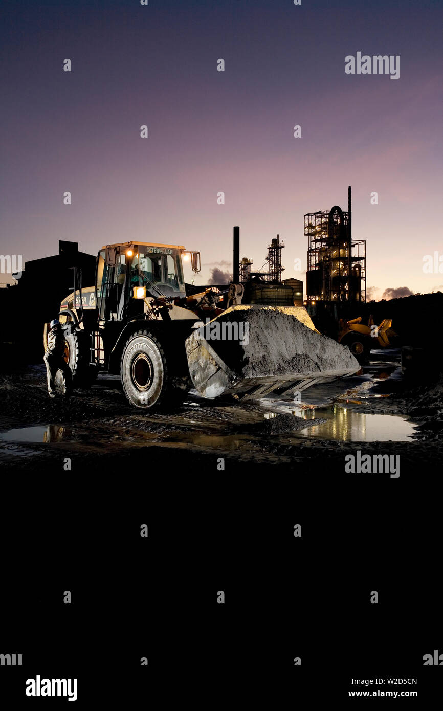 Estrazione, gestione e trasporto di sabbie minerali di titanio. Caricatore frontale che sposta il concentrato di sabbia minerale pesante dal cumulo di stock all'impianto di separazione. Foto Stock