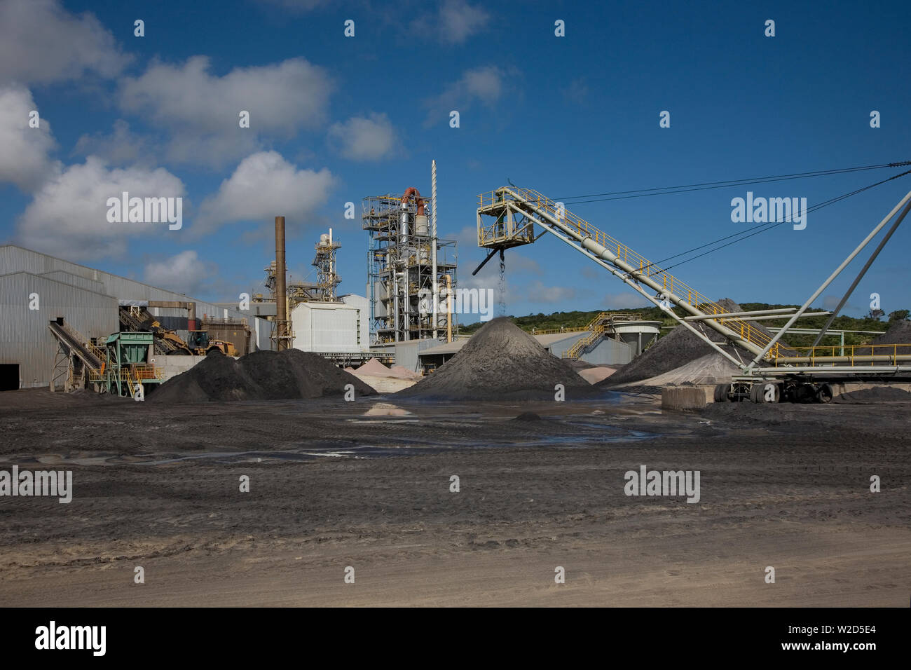 Estrazione, gestione e trasporto di sabbie minerali di titanio. Caricatore frontale dietro lo spostamento di concentrato di sabbia minerale pesante dal cumulo di scorte alla tramoggia Foto Stock