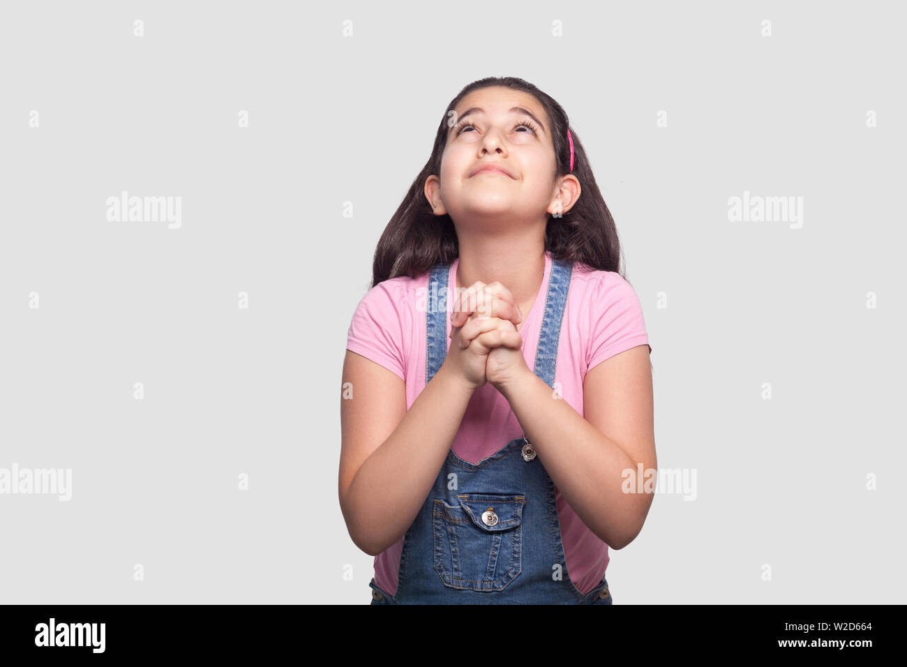 Il mio Dio mi aiuta a. Ritratto di speranzoso triste bruna giovane ragazza in t-shirt rosa e blu denim tuta in piedi, guardando verso l'alto e la preghiera o supplica. indo Foto Stock