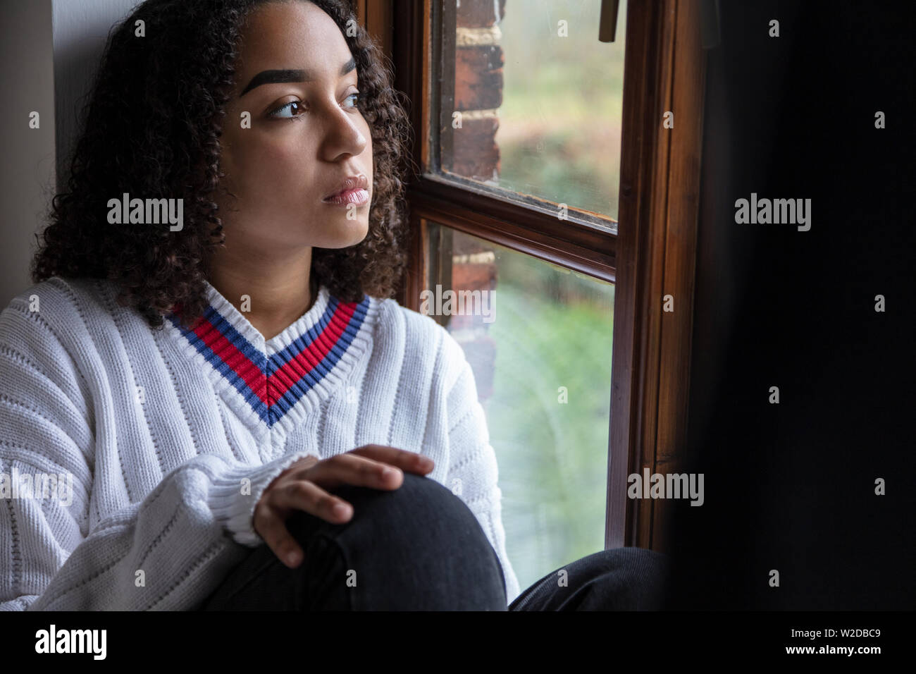 Bellissima gara di misto biracial americano africano ragazza adolescente di sesso femminile donna giovane triste premuto o pensieroso guardando fuori della finestra Foto Stock