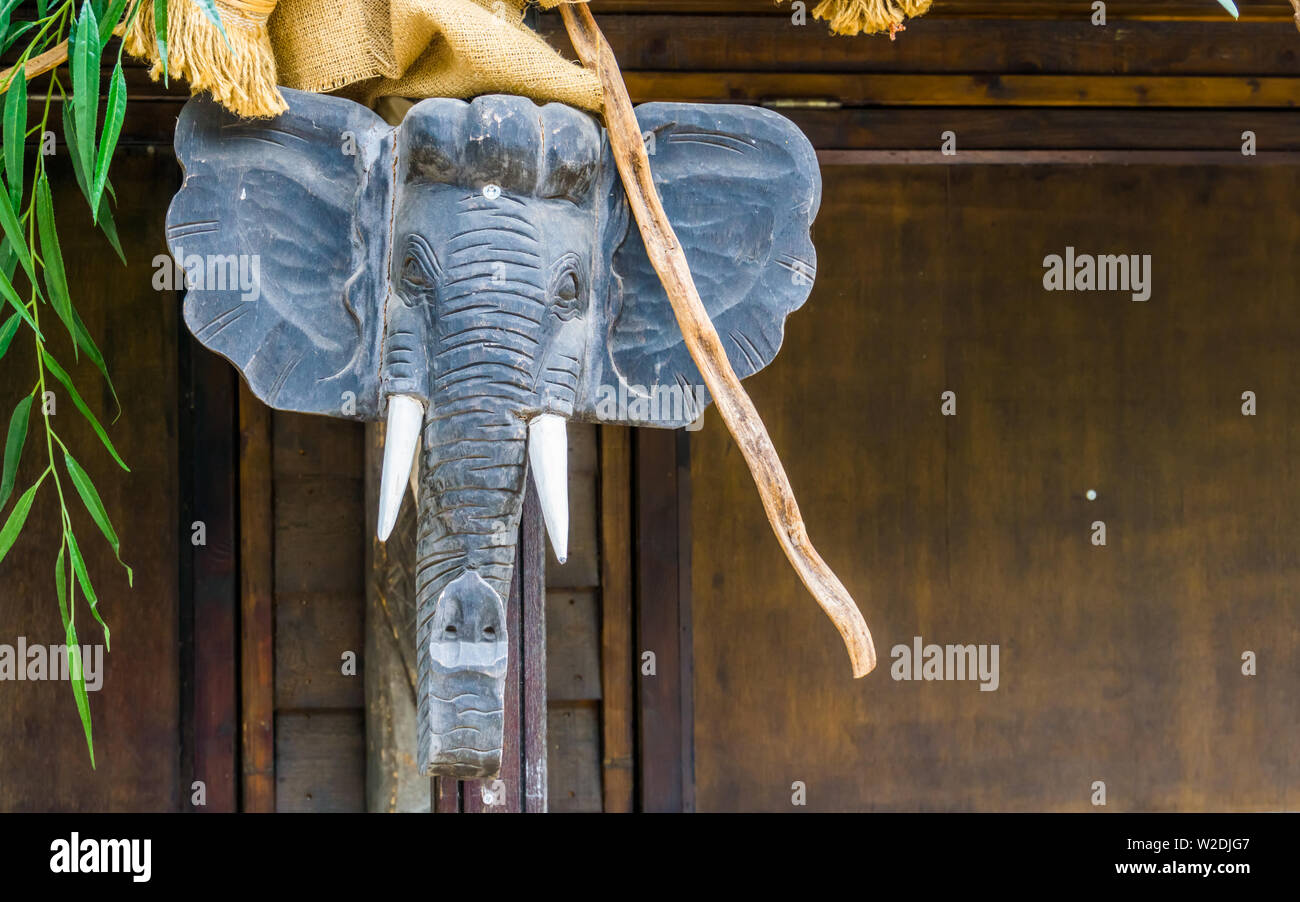 Testa di elefante scultura appesi ad un palo di legno, africane tradizionali decorazioni home Foto Stock