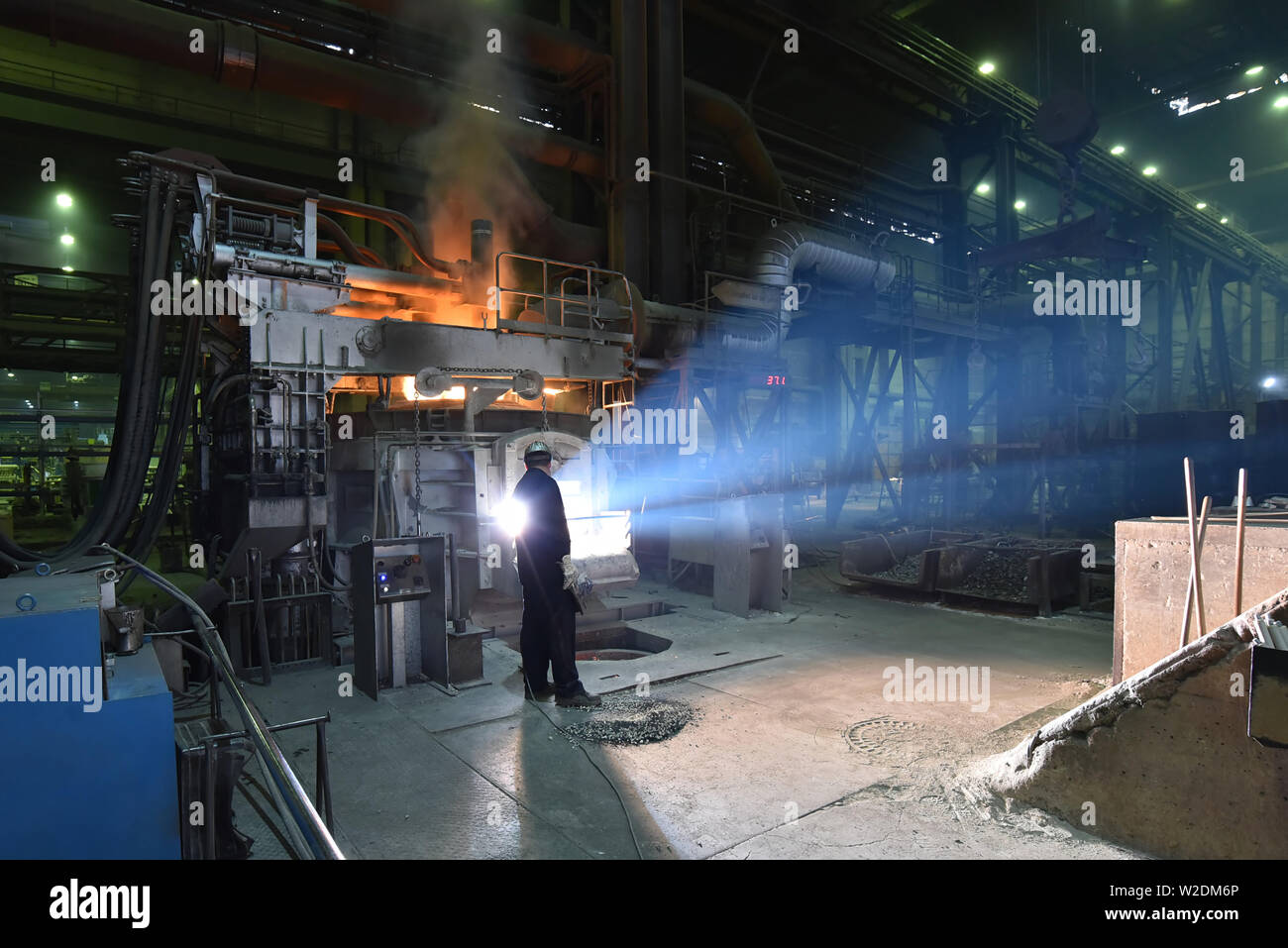 I lavoratori di attrezzature di protezione in una fonderia durante la produzione di componenti in acciaio - sul posto di lavoro in fabbrica industriale Foto Stock