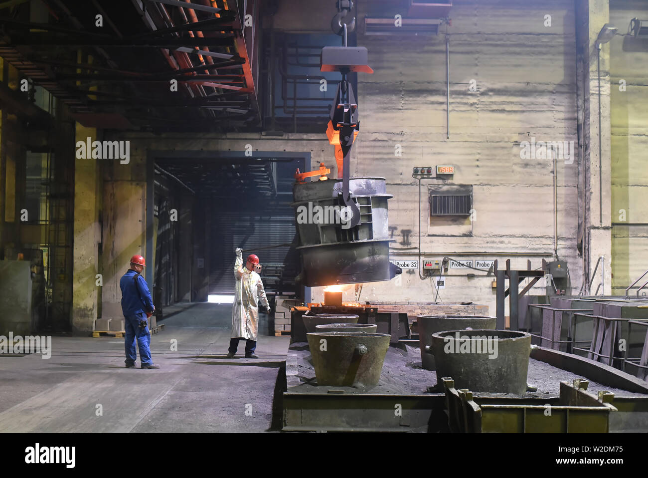 I lavoratori di attrezzature di protezione in una fonderia durante la produzione di componenti in acciaio - sul posto di lavoro in fabbrica industriale Foto Stock