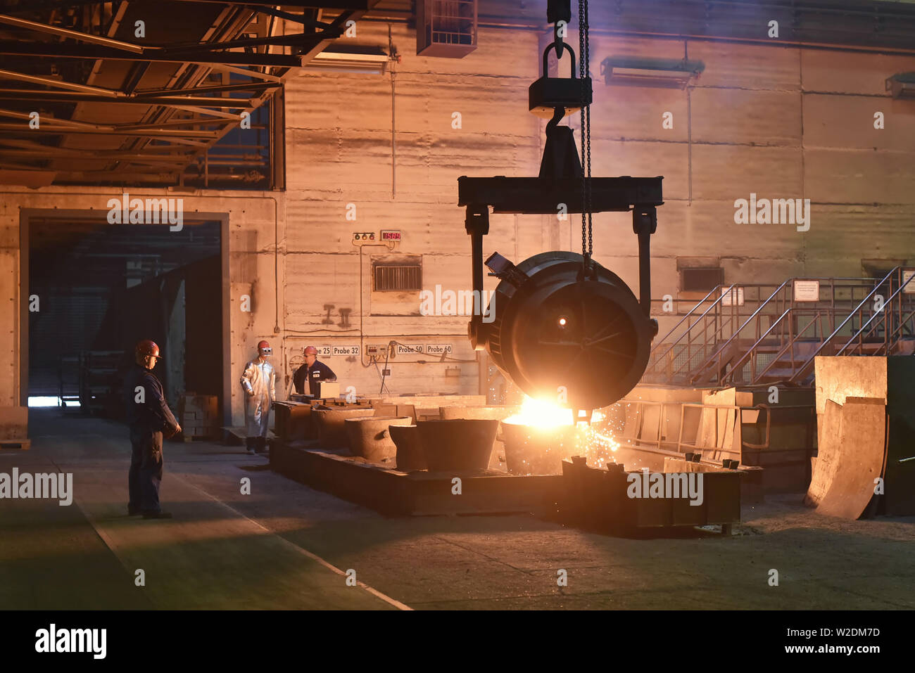 I lavoratori di attrezzature di protezione in una fonderia durante la produzione di componenti in acciaio - sul posto di lavoro in fabbrica industriale Foto Stock
