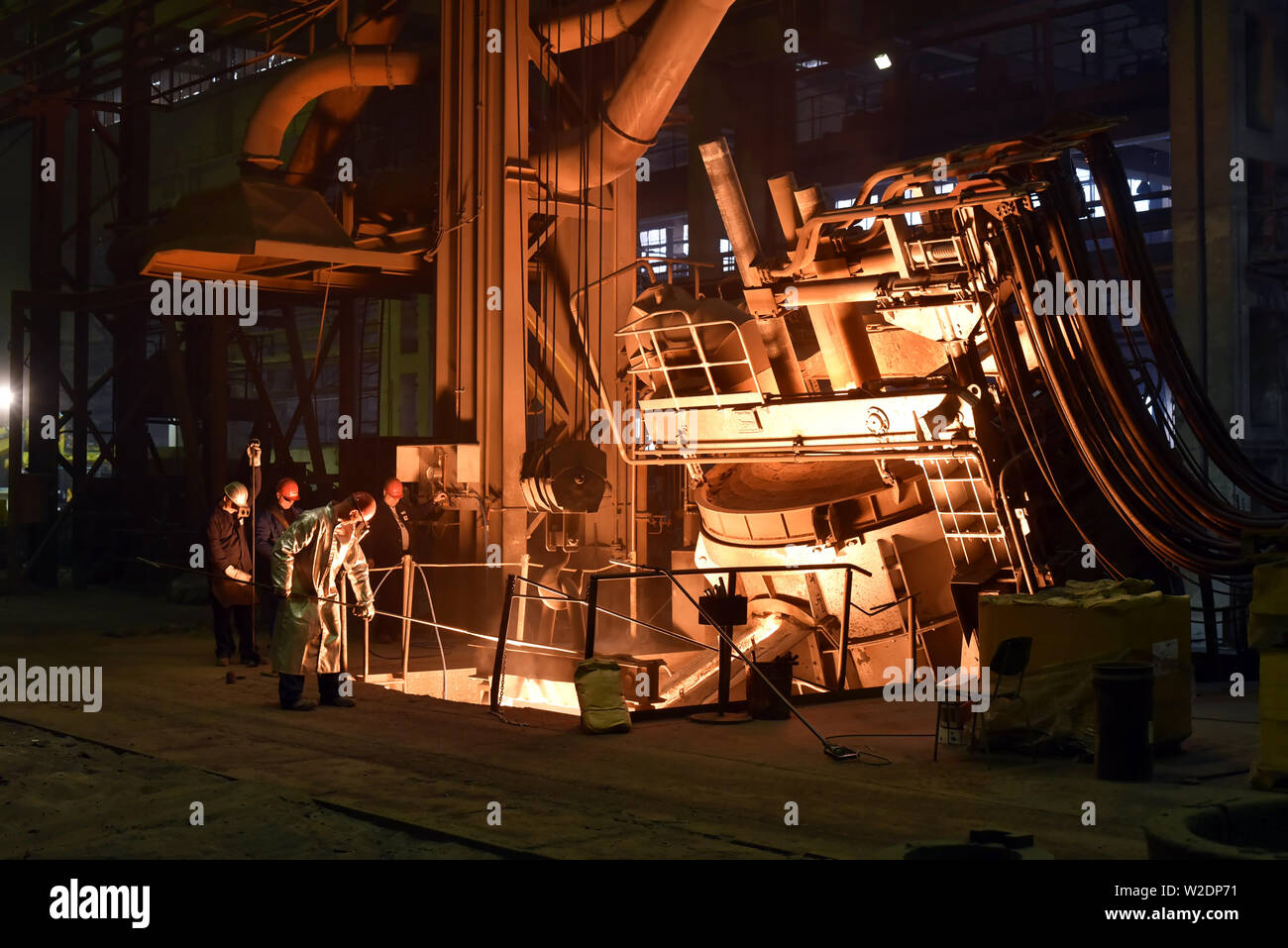 I lavoratori di attrezzature di protezione in una fonderia durante la produzione di componenti in acciaio - sul posto di lavoro in fabbrica industriale Foto Stock