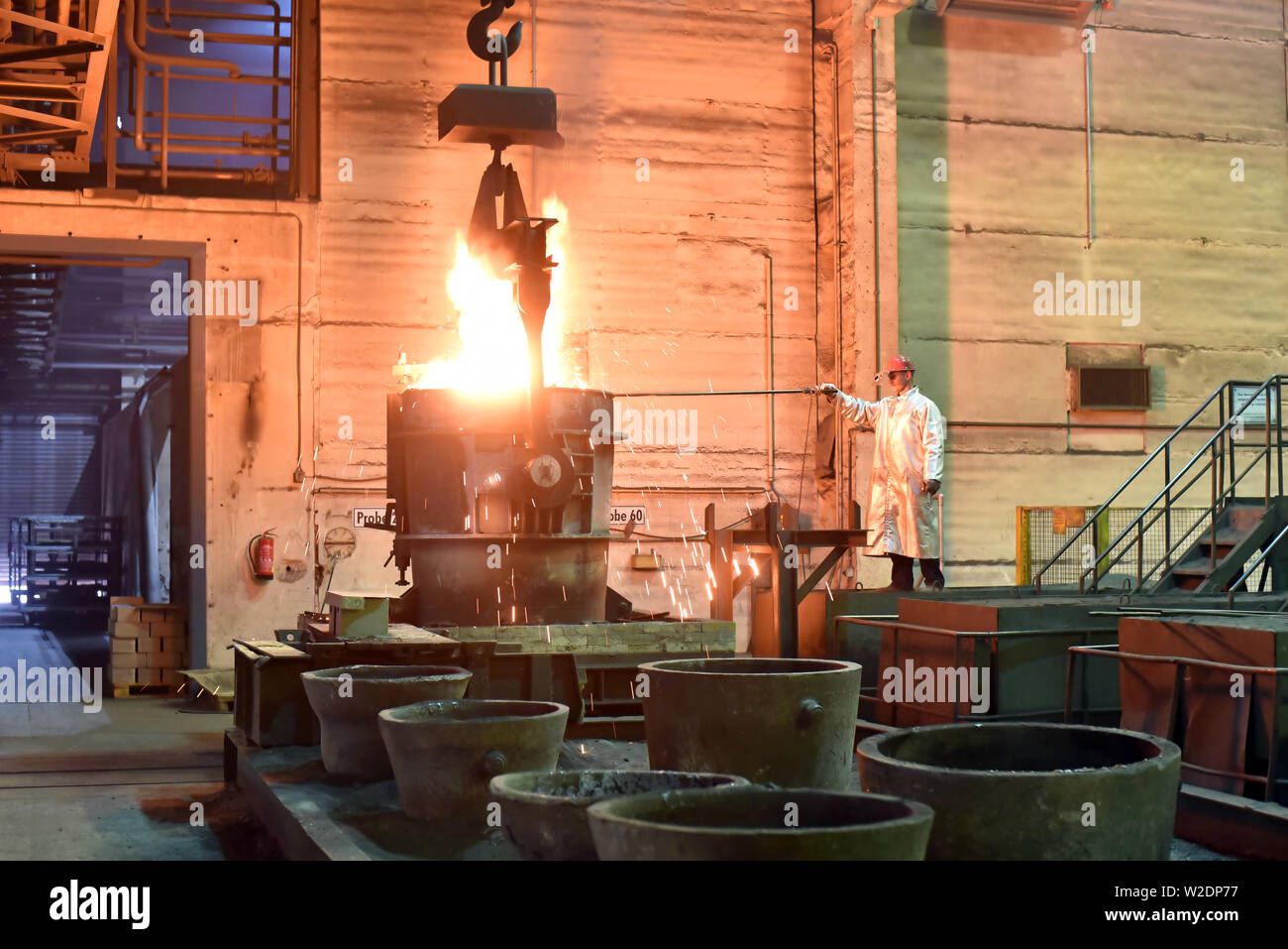 I lavoratori di attrezzature di protezione in una fonderia durante la produzione di componenti in acciaio - sul posto di lavoro in fabbrica industriale Foto Stock