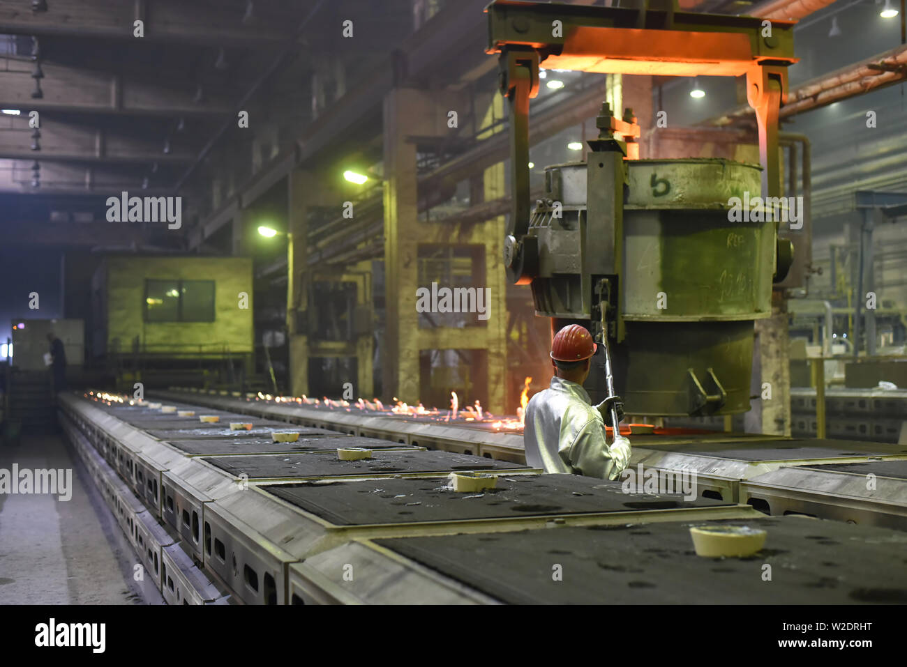 I lavoratori di attrezzature di protezione in una fonderia durante la produzione di componenti in acciaio - sul posto di lavoro in fabbrica industriale Foto Stock