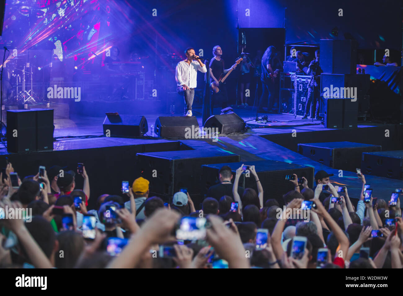 LVIV, Ucraina - 18 Giugno 2019: rock band cantante sul palco con microfono si affollano intorno Stadio riprese su telefoni. music fest Foto Stock