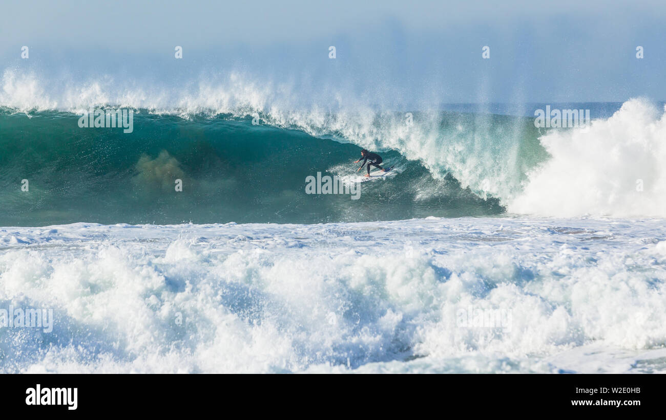 Oceano onda cava grande crash acqua blu con unidentified surfer surf di metropolitana incontrano facce nature power. Foto Stock