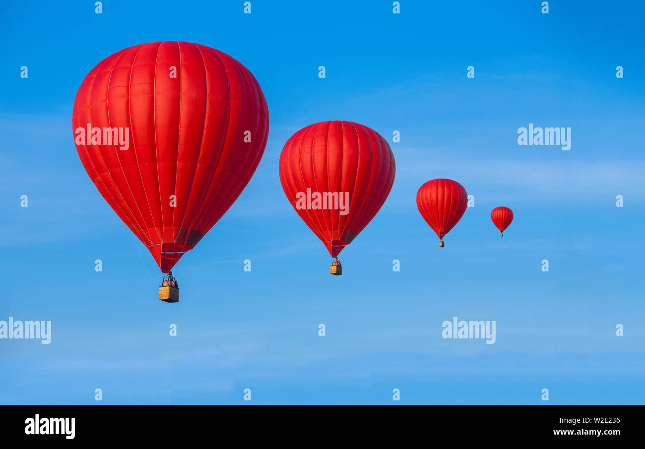 Quattro Red i palloni ad aria calda nel cielo blu con nuvole bianche Foto Stock