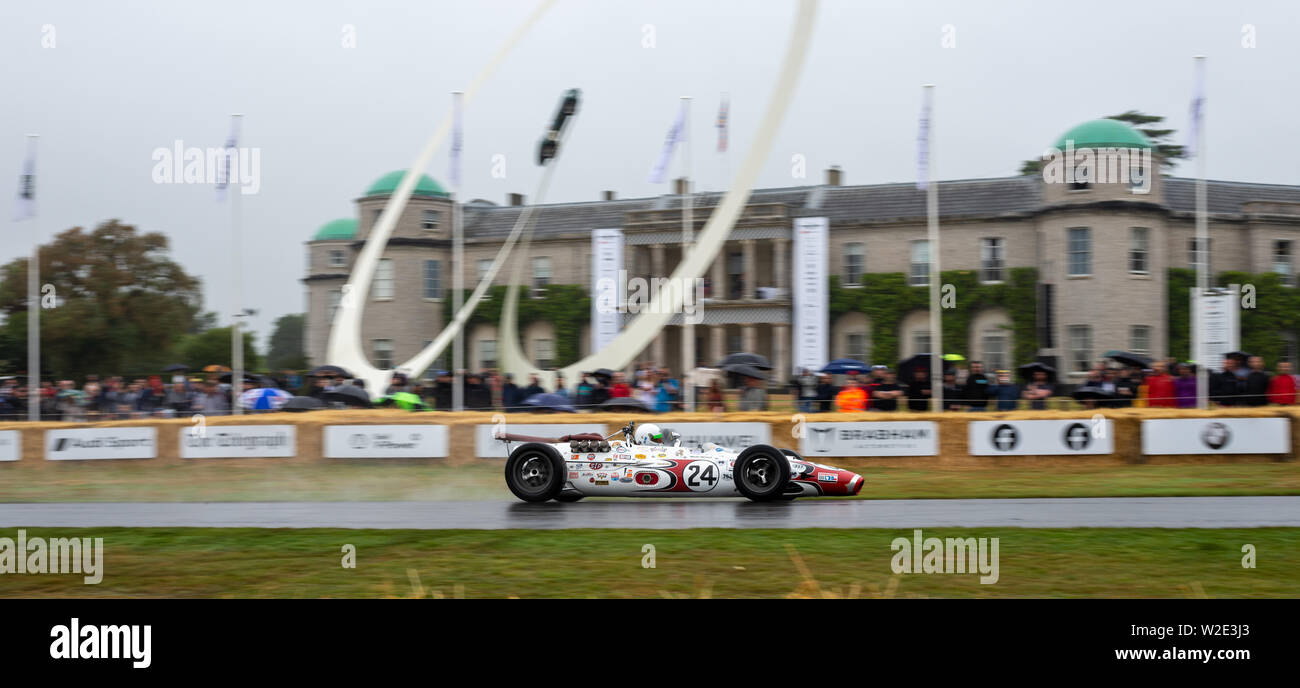 Un Indy car velocità oltre la scultura centrale sotto la pioggia a Goodwood Festival della velocità 2019 Foto Stock