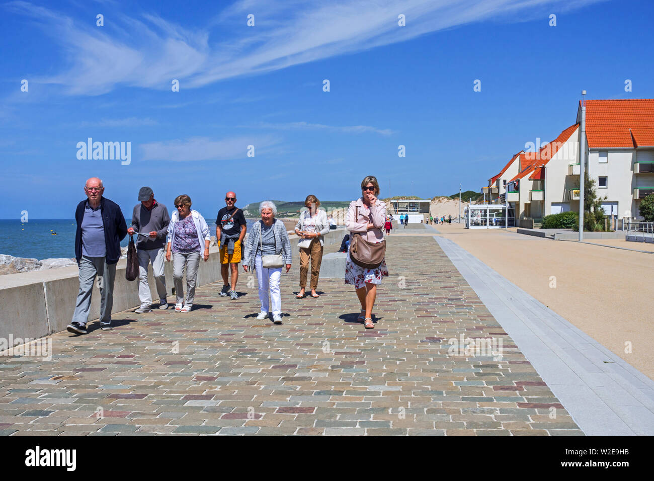 Anziani turisti a piedi lungo la passeggiata a mare resort Wissant in estate lungo la Côte d'Opale, Pas-de-Calais, Hauts-de-France, Francia Foto Stock