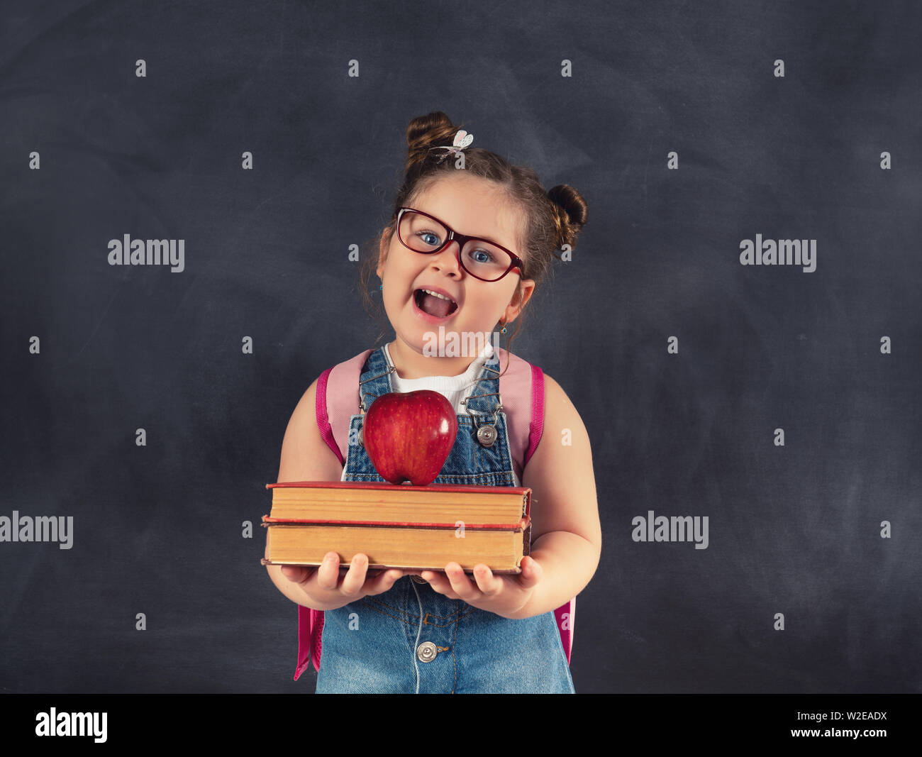 Poco carino bambino azienda libri sulla lavagna.concetto di istruzione Foto Stock