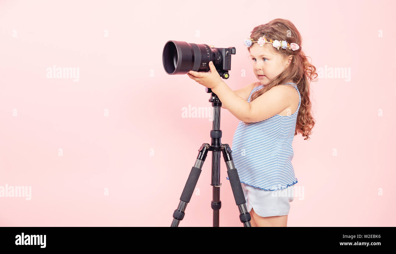 Bambina tenere la fotocamera e sorridente su sfondo rosa. Foto Stock