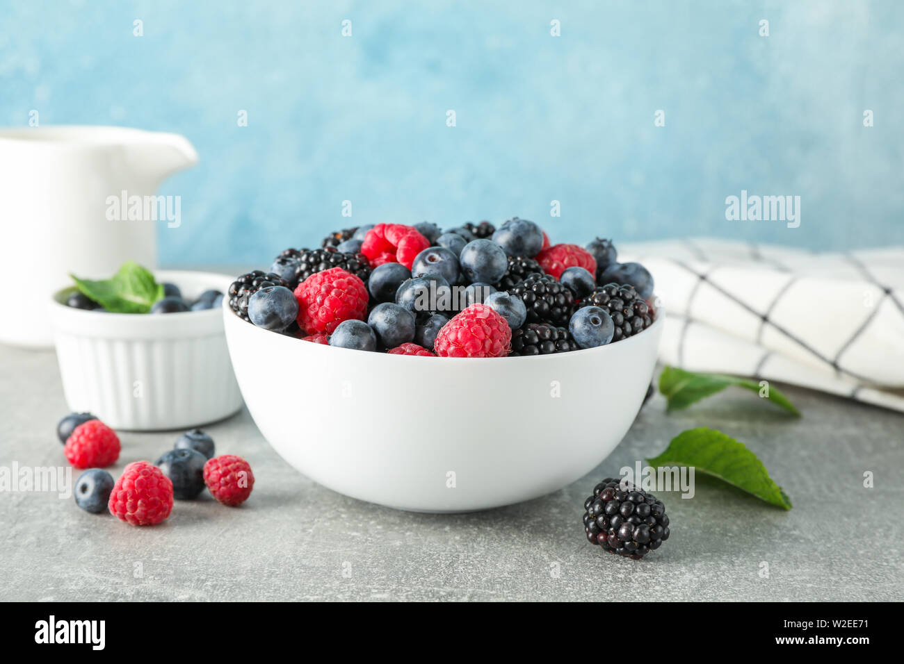 Composizione con piatti in ceramica e bacche sulla tabella grigia Foto Stock