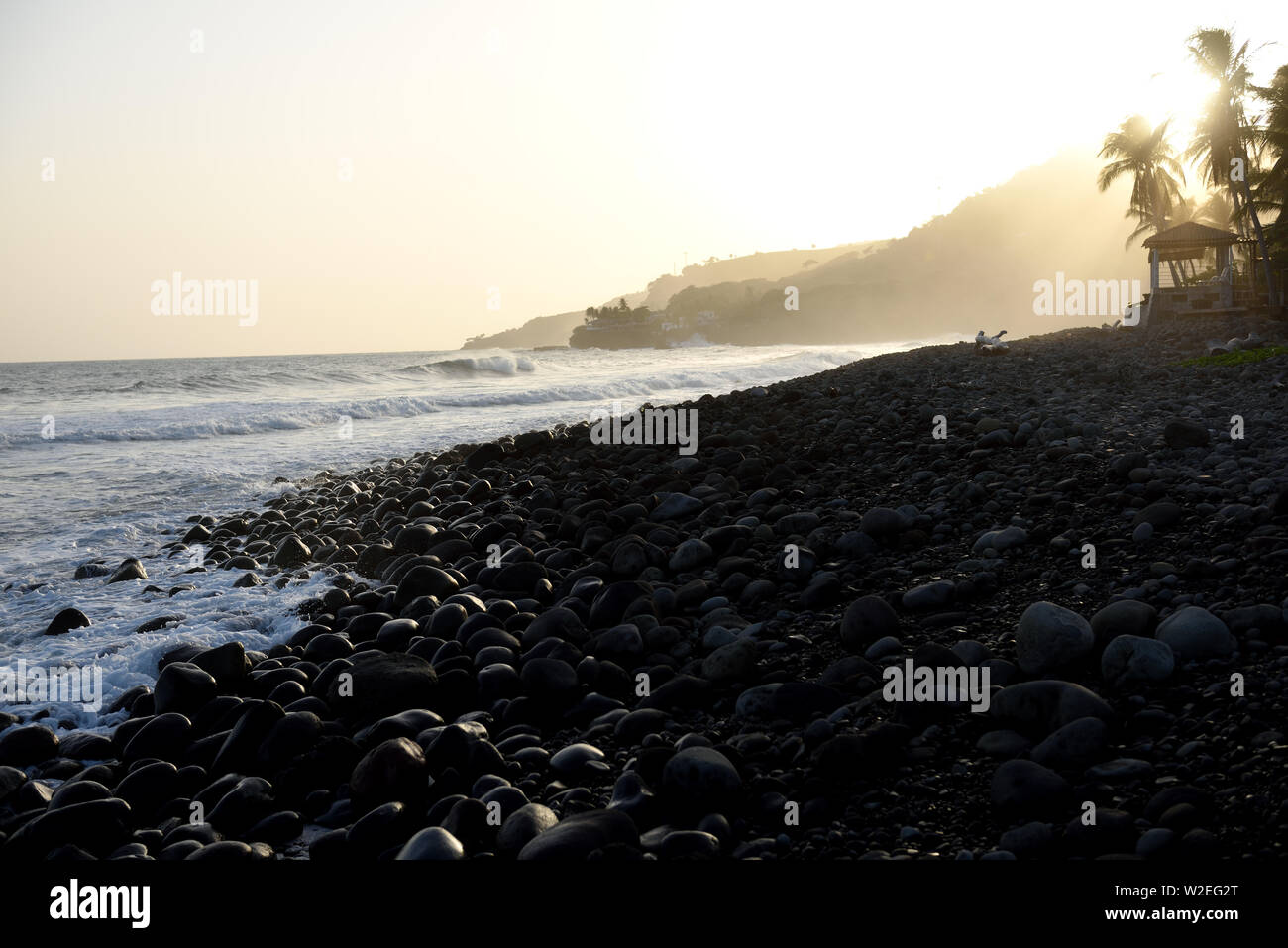 Le onde del mare contro rocce ciottoli al tramonto tropicale in El Salvador. Foto Stock