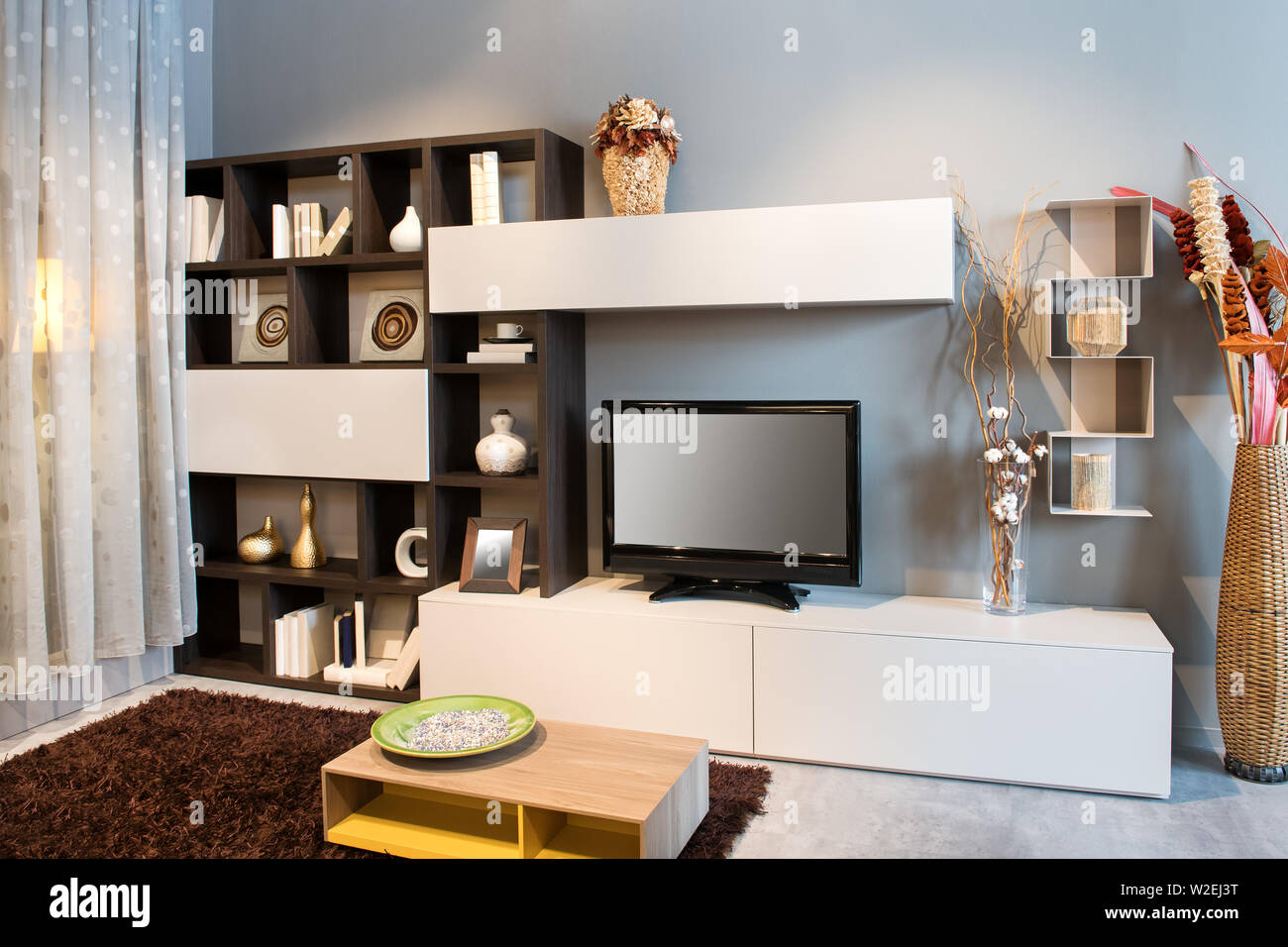 Soggiorno moderno o den interno con TV su una piccola unità a parete con display per ornamenti e libri illuminato con luci Foto Stock