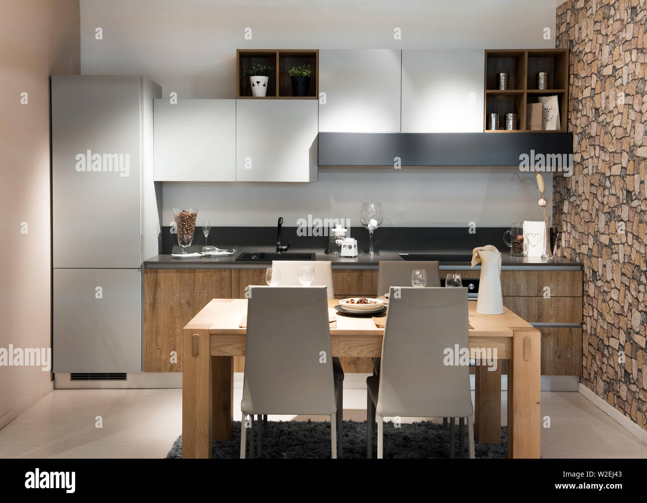 Compact moderna cucina o angolo cottura con costruito in armadi e apparecchi piano aperto per un piccolo design contemporaneo chunky tavolo e sedie Foto Stock