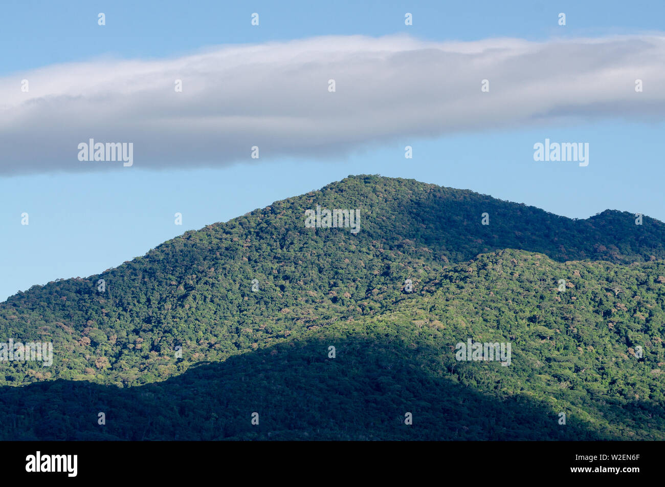 Una vista di una collina con un cielo terso e cloud top Foto Stock